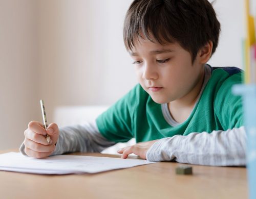 Happy boy using pencil drawing or sketching on paper, Portrait  kid siting on table doing homework, Child enjoy art and craft activity at home, Education concept
