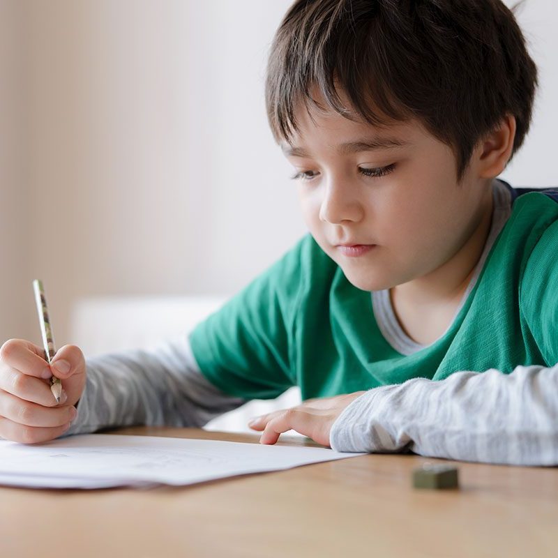 Happy boy using pencil drawing or sketching on paper, Portrait  kid siting on table doing homework, Child enjoy art and craft activity at home, Education concept