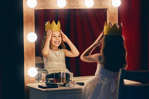Cute little actress. Child girl in Princess costume on the background of theatrical scenes and mirrors.