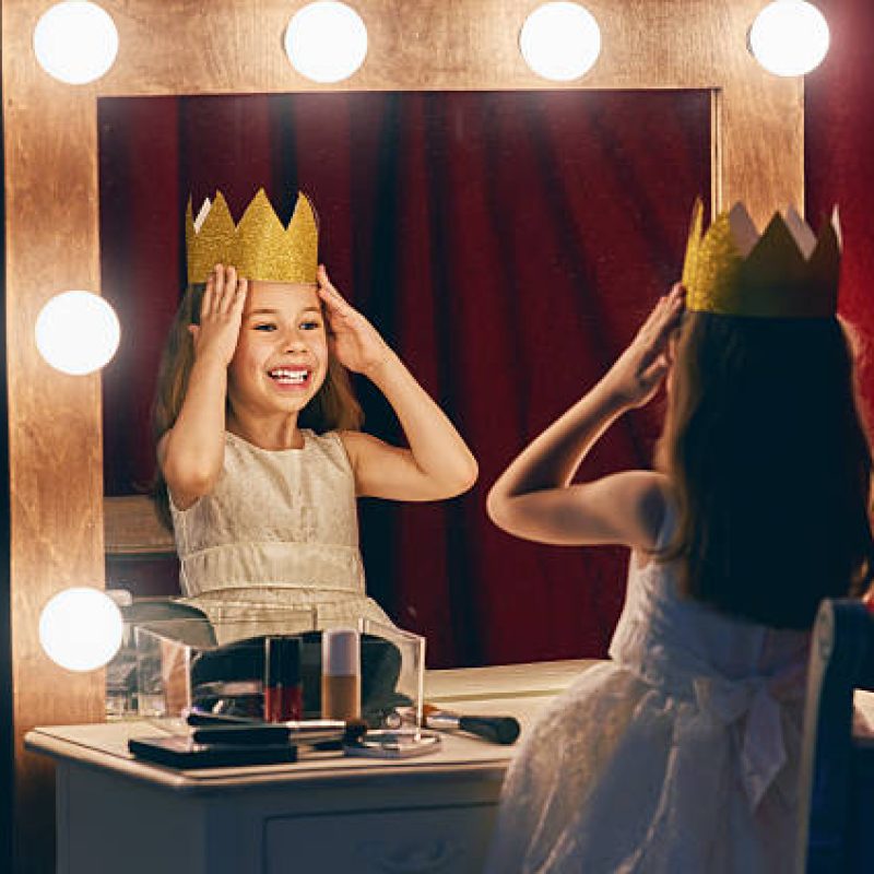 Cute little actress. Child girl in Princess costume on the background of theatrical scenes and mirrors.